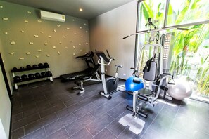 A gym with exercise equipment, a bench, dumbbells, and a window with a view of greenery. - Tranquil Rawai villa with pool and tropical garden (Tambon Rawai)