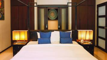 A hotel room with a large bed, two bedside tables with lamps, a decorative wall piece, and a wooden door with frosted glass panels.