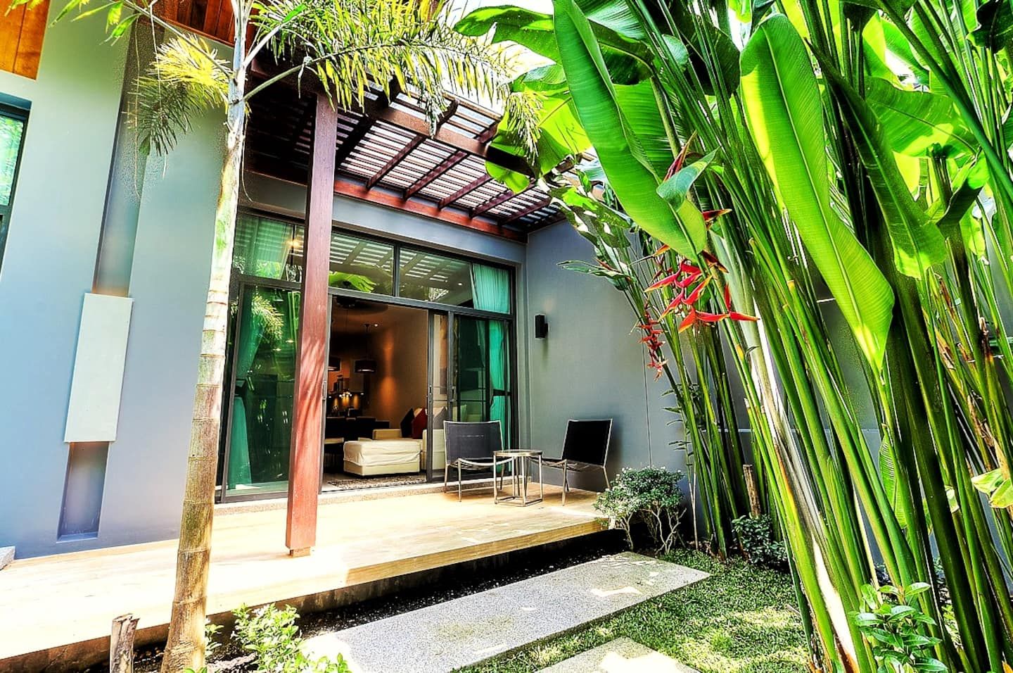 A modern house with a patio, a dining area, and a large window overlooking the garden.