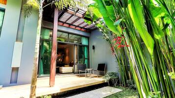 A modern house with a patio, a dining area, and a large window overlooking the garden.