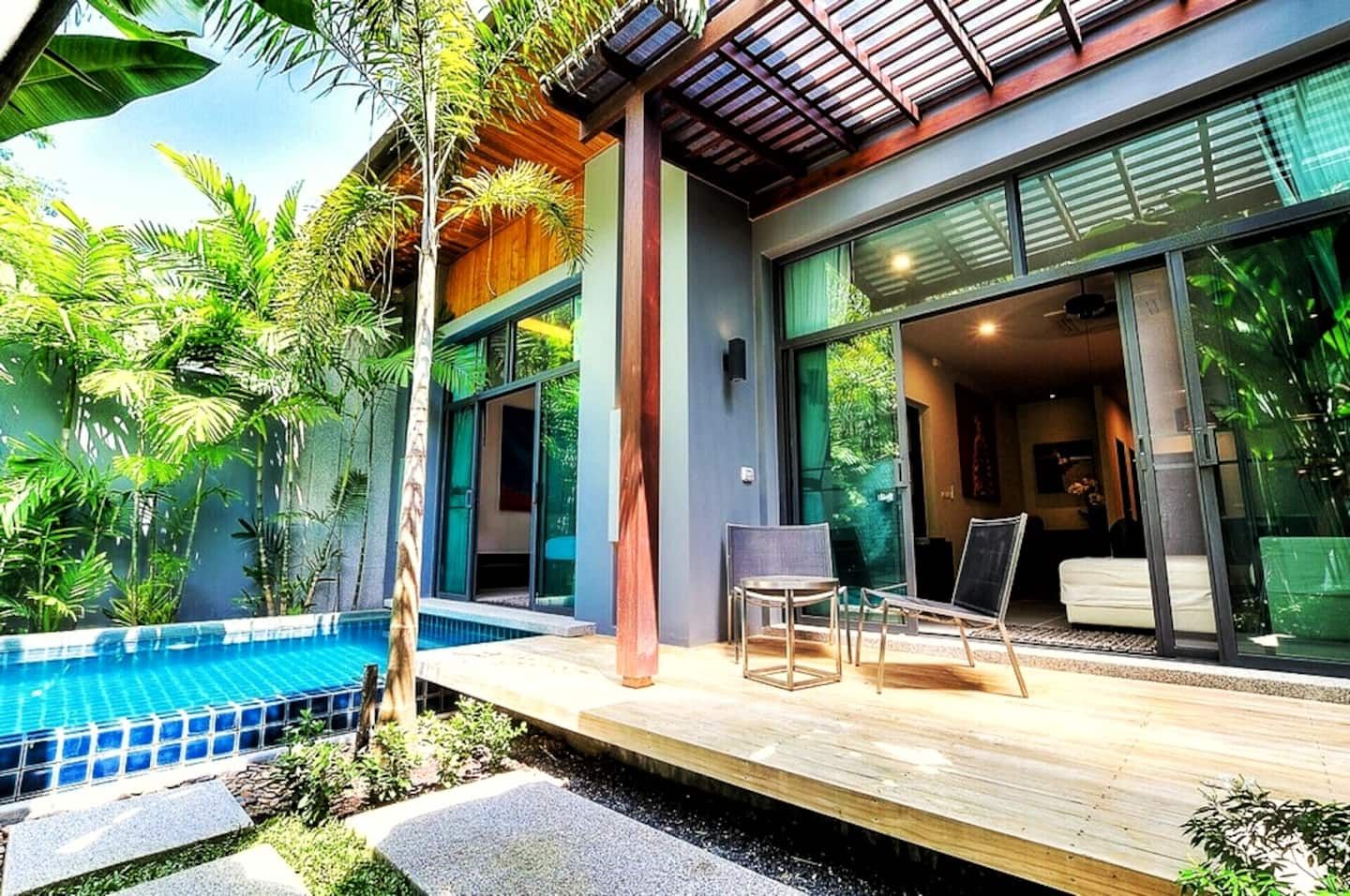 A modern house with a pool, a covered patio, and a bedroom with a large window.