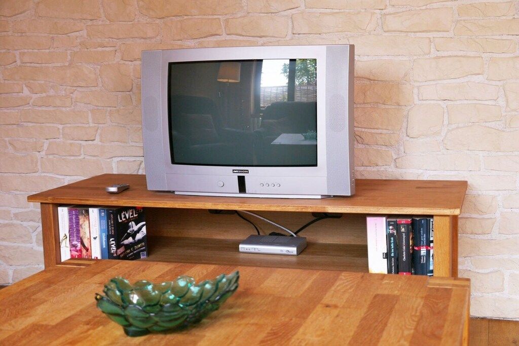 Ein Fernseher auf einem Holzboden mit darunterliegenden Bücherregalen.