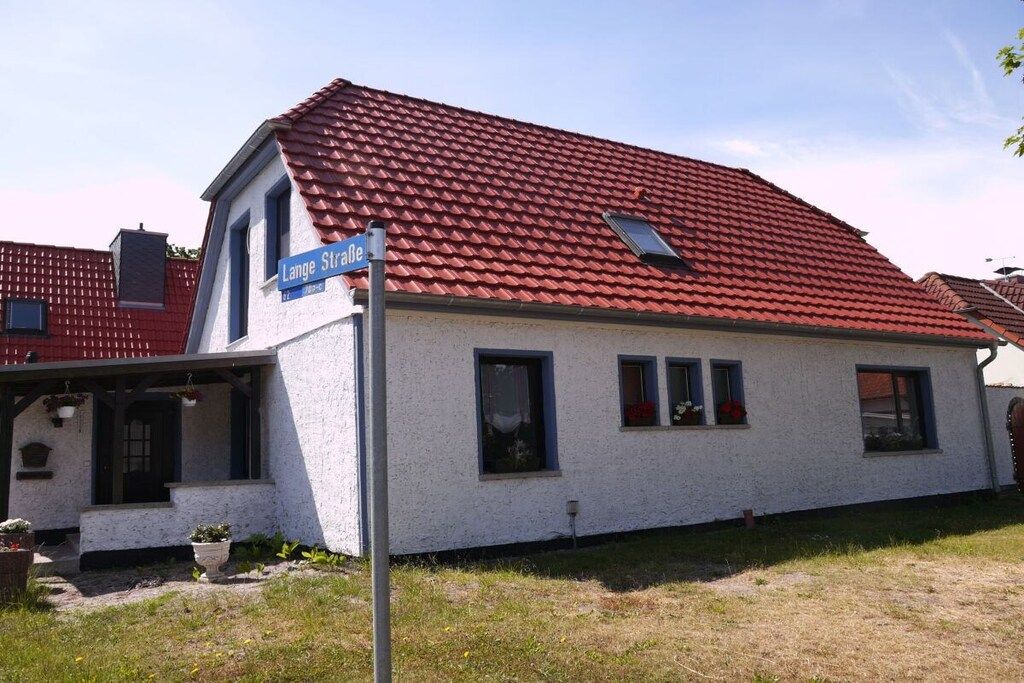 Une maison avec un toit recouvert de tuiles rouges, une façade blanche et un panneau de rue bleu indiquant « Lange Straße ».