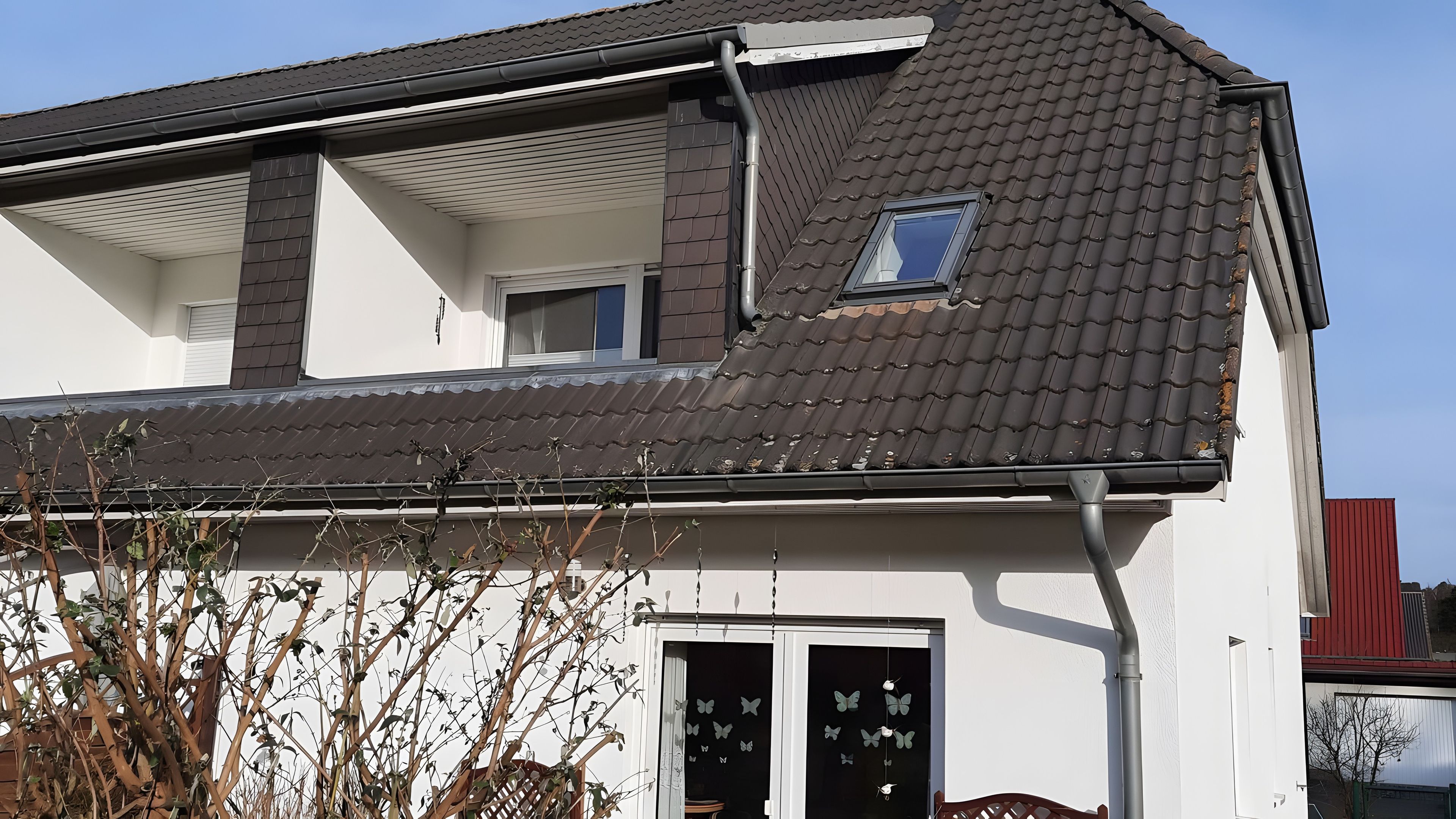 A two-story house with a tiled roof, a visible window, and a door with a butterfly decal.