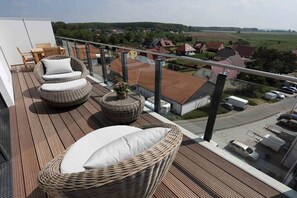 A balcony with wicker furniture, a view of a residential area, and a clear sky. - Holiday apartment in Glowe with swimming pool (Glowe)