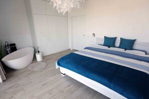 A modern bedroom with a large bed, a built-in bathtub, and a minimalist design. - Holiday apartment in Glowe with swimming pool (Glowe)