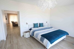 Une chambre à coucher moderne avec un grand lit, des tables de chevet et un luminaire suspendu.