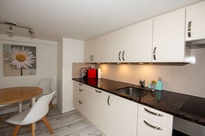 Een moderne keuken met witte kasten, een zwart aanrecht en een roestvrijstalen spoelbak.