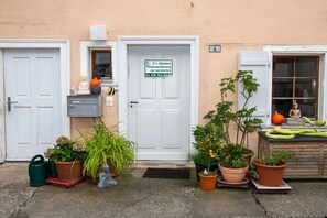 A two-room apartment with a door marked for rent, potted plants, and a small statue on the doorstep. - Holiday apartment with 2 bedrooms (Ermatingen)
