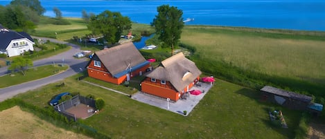 A rural property with a large house, a smaller building with a thatched roof, and a boat docked by the water.