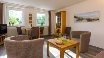 A modern living room with a dining area, a television, and a painting on the wall.