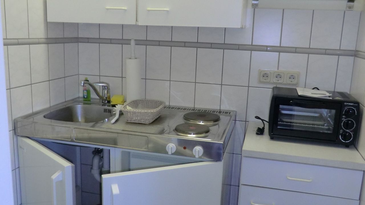 Una cucina compatta con lavello, fornello e forno tostatutto.