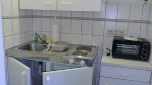 Una cocina compacta con lavamanos, estufa y horno tostador.