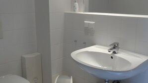Un bany amb un lavabo blanc, un vàter i una zona de dutxa.