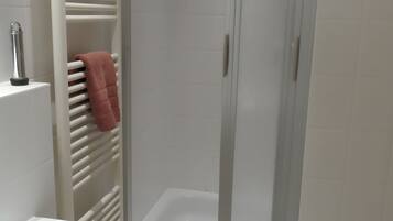 Ein Badezimmer mit einer weißen Badewanne, einem Handtuchhalter mit einem rosafarbenen Handtuch und einer weißen Fliesenwand.
