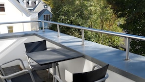 Ein Balkon im Freien mit einem Metallgeländer, einem Tisch und zwei Stühlen.