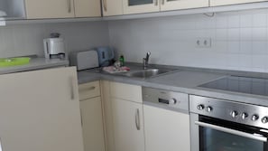 Eine Küche mit weißen Schränken, einer Edelstahl-Spüle, einem Einbauofen und einem Toaster.