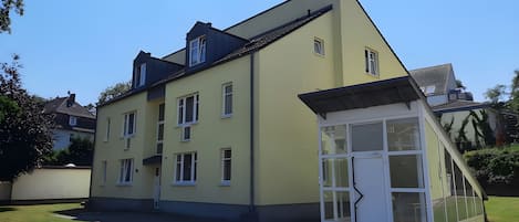 A two-story building with multiple windows and a small attached structure with glass doors.