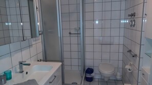 Ein modernes Badezimmer mit Badewanne, Toilette und Dusche.