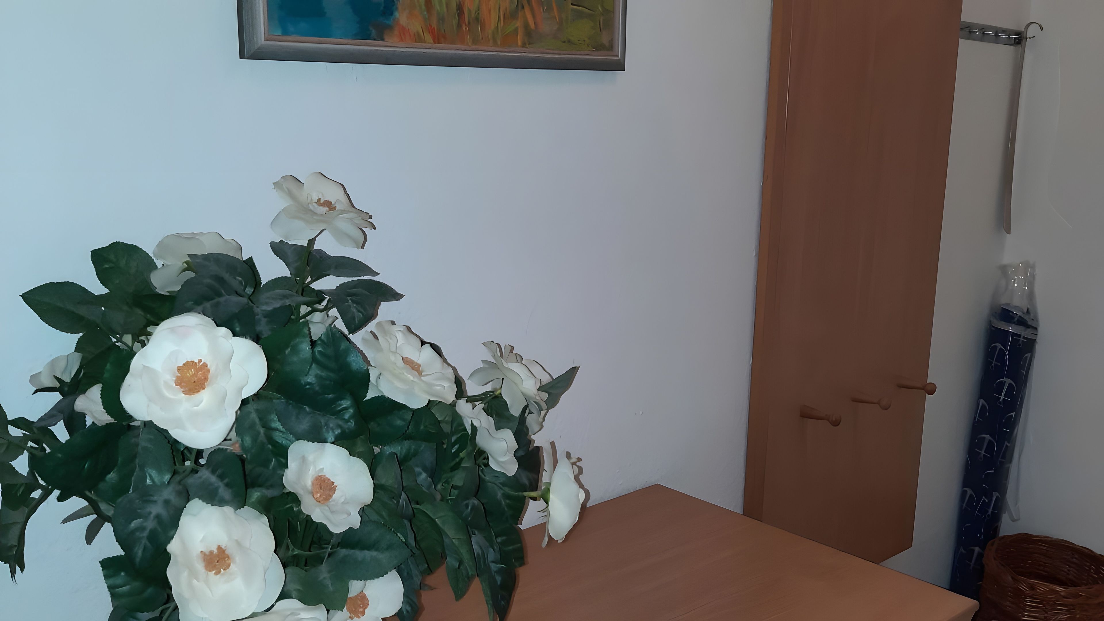 A room with a wooden door, a small table, and a wall-mounted painting.