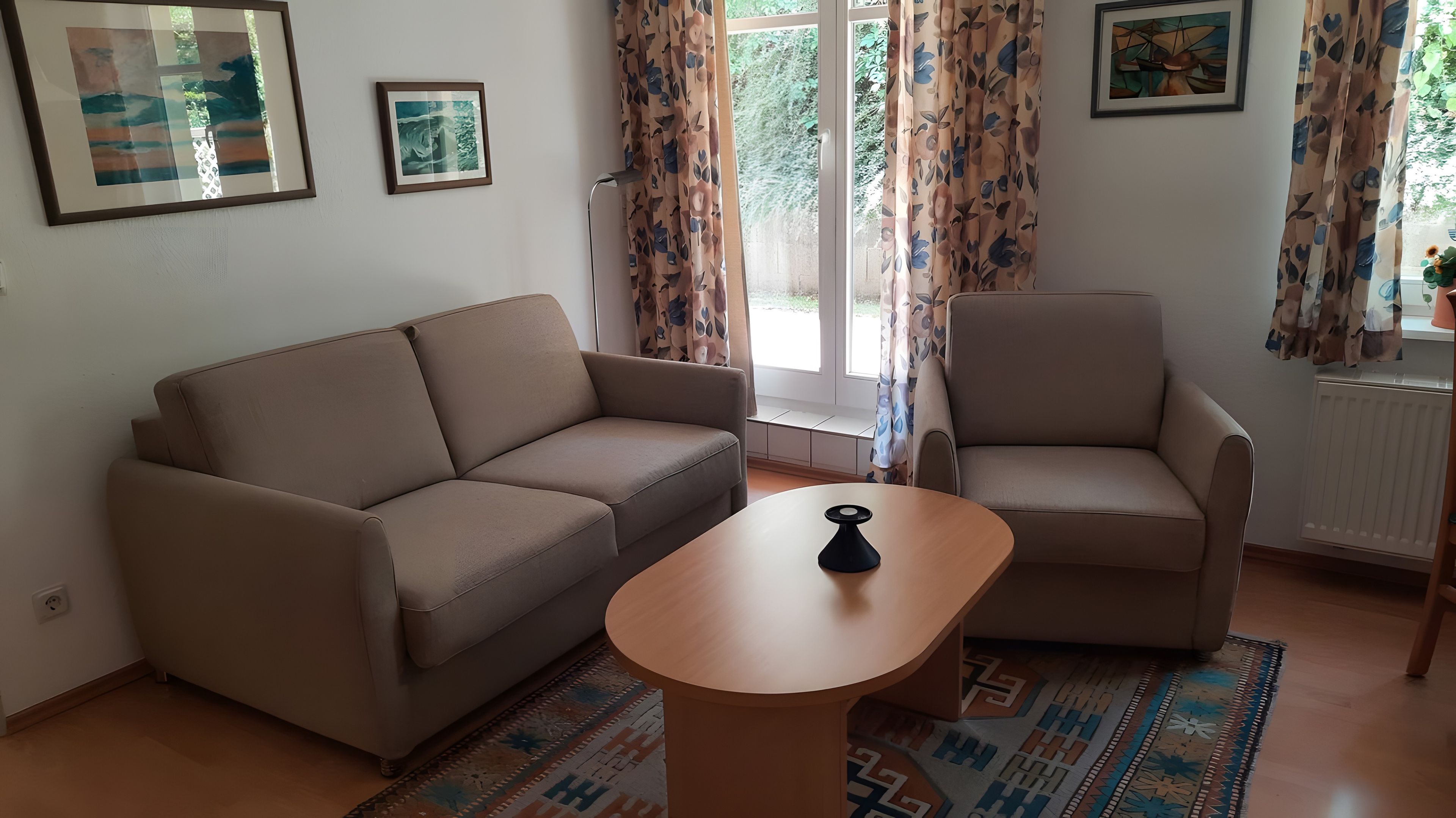 Una sala de estar con un sofá, un sillón y una pequeña mesa de madera.