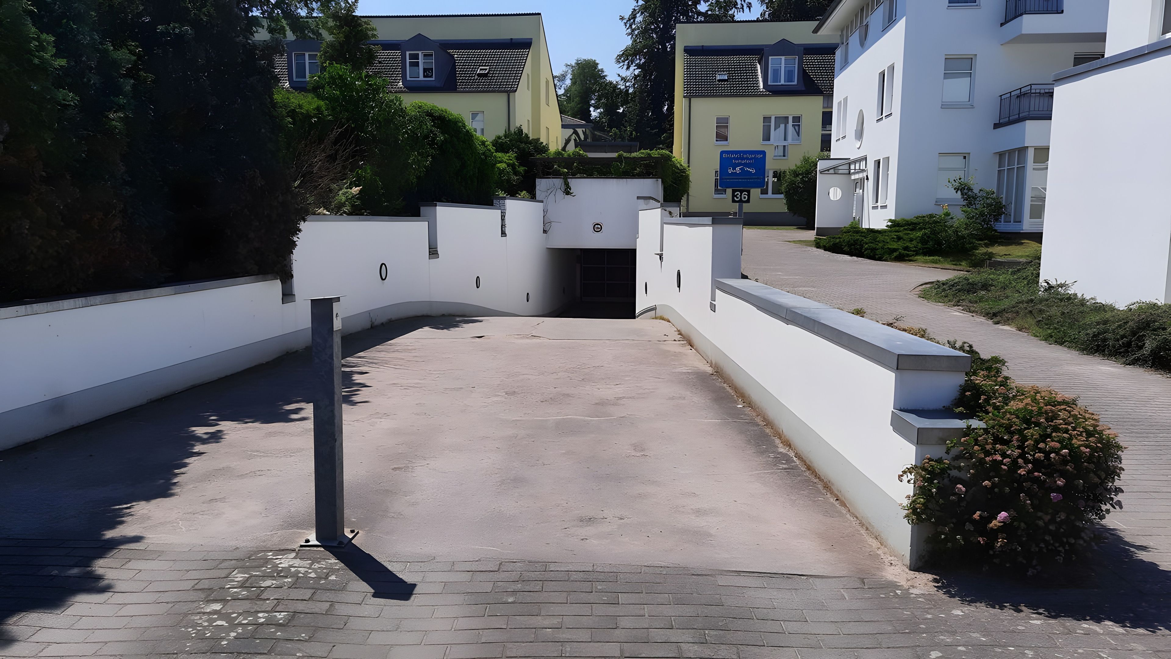 Ein begrenzter Zugang zu einem Wohngebiet, mit einer gepflasterten Auffahrt, die zu einem Hauseingang führt.