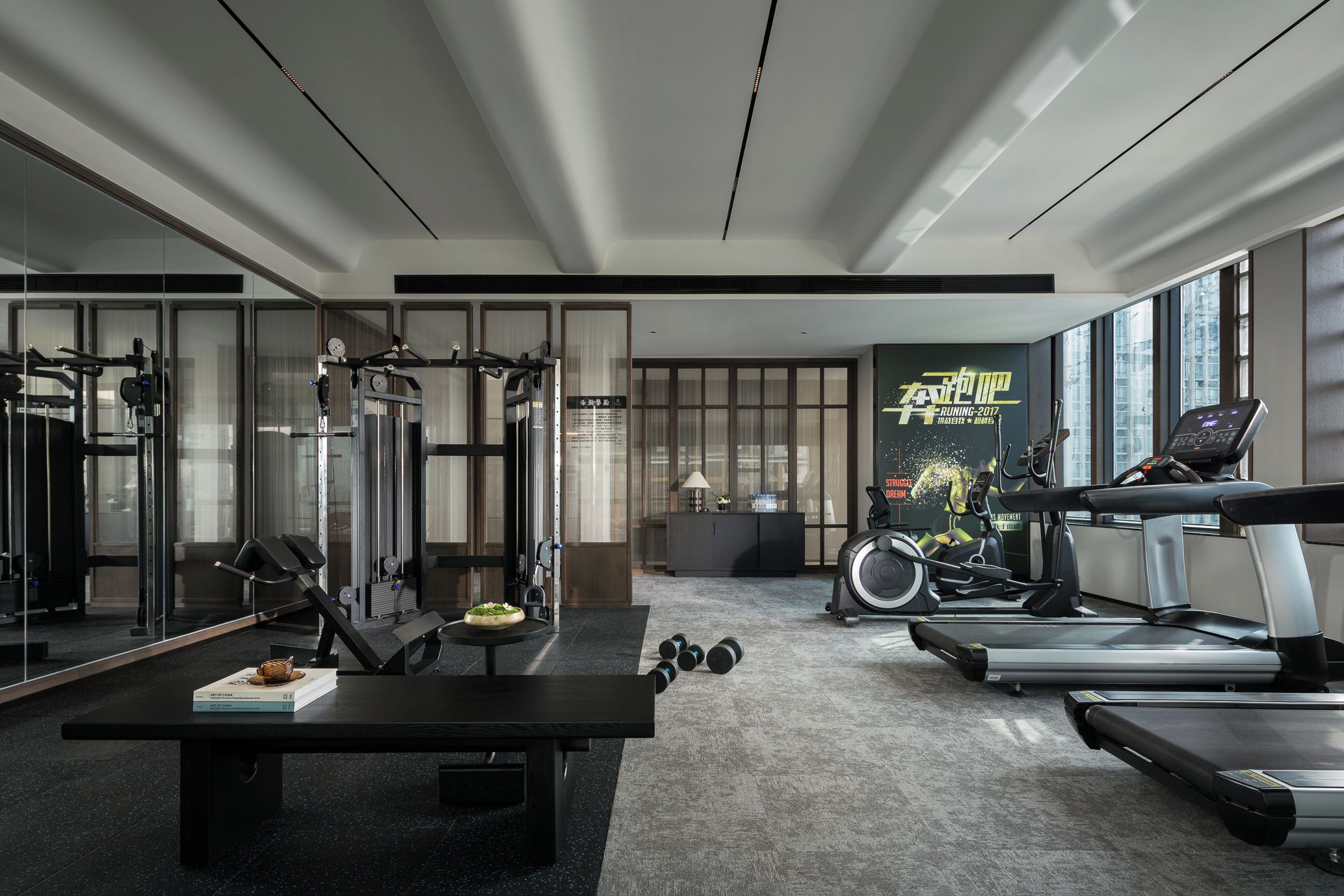 A modern gym with exercise equipment, a treadmill, and a wall with motivational posters.