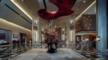 A spacious lobby with a central floral arrangement, high ceilings, and modern lighting fixtures.