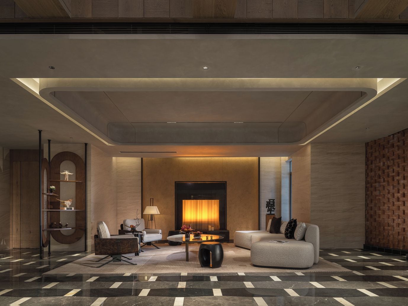 A modern lobby with a sofa, armchairs, a coffee table, and a fireplace.