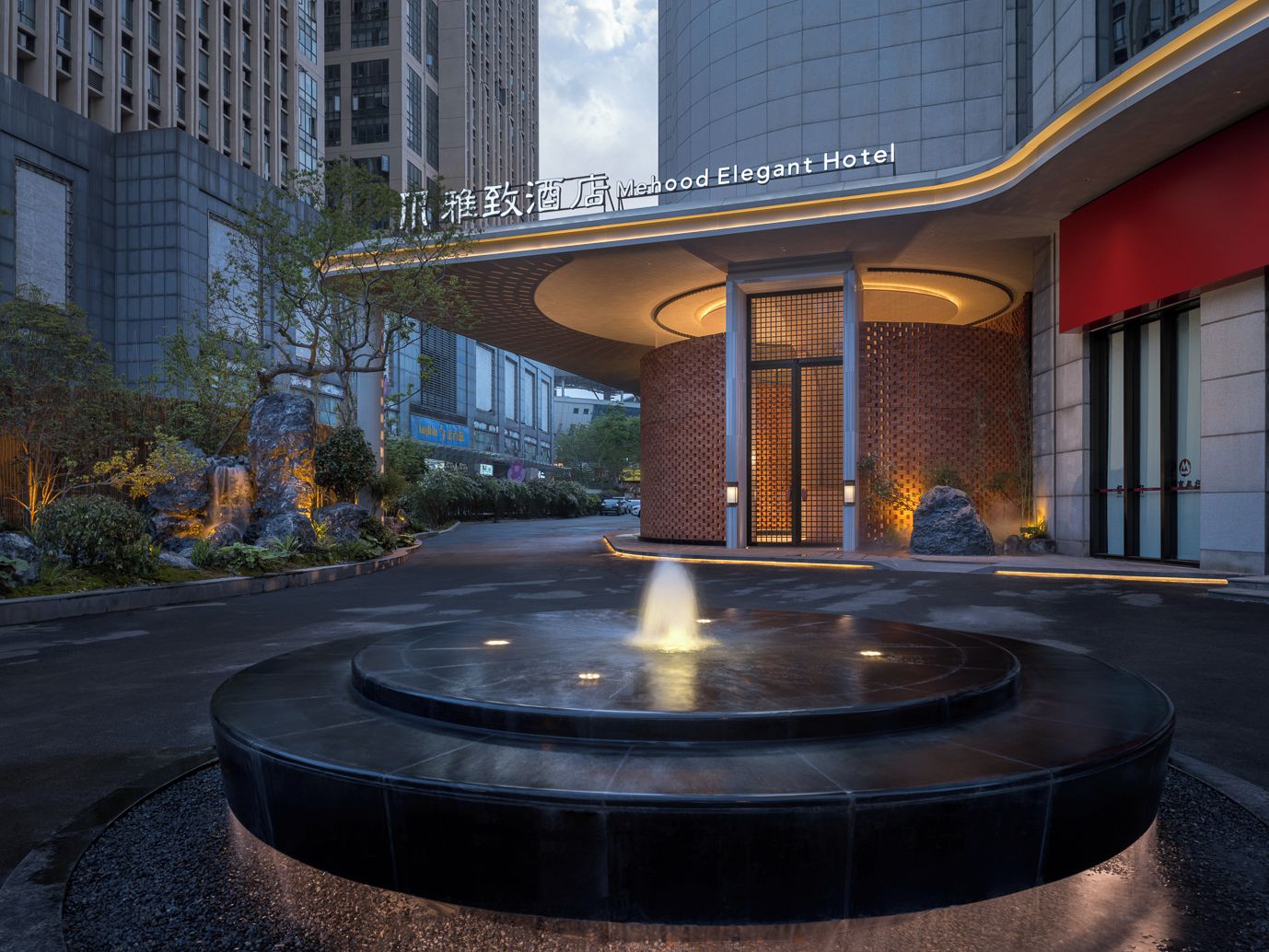 A modern hotel entrance with a water feature in the foreground.