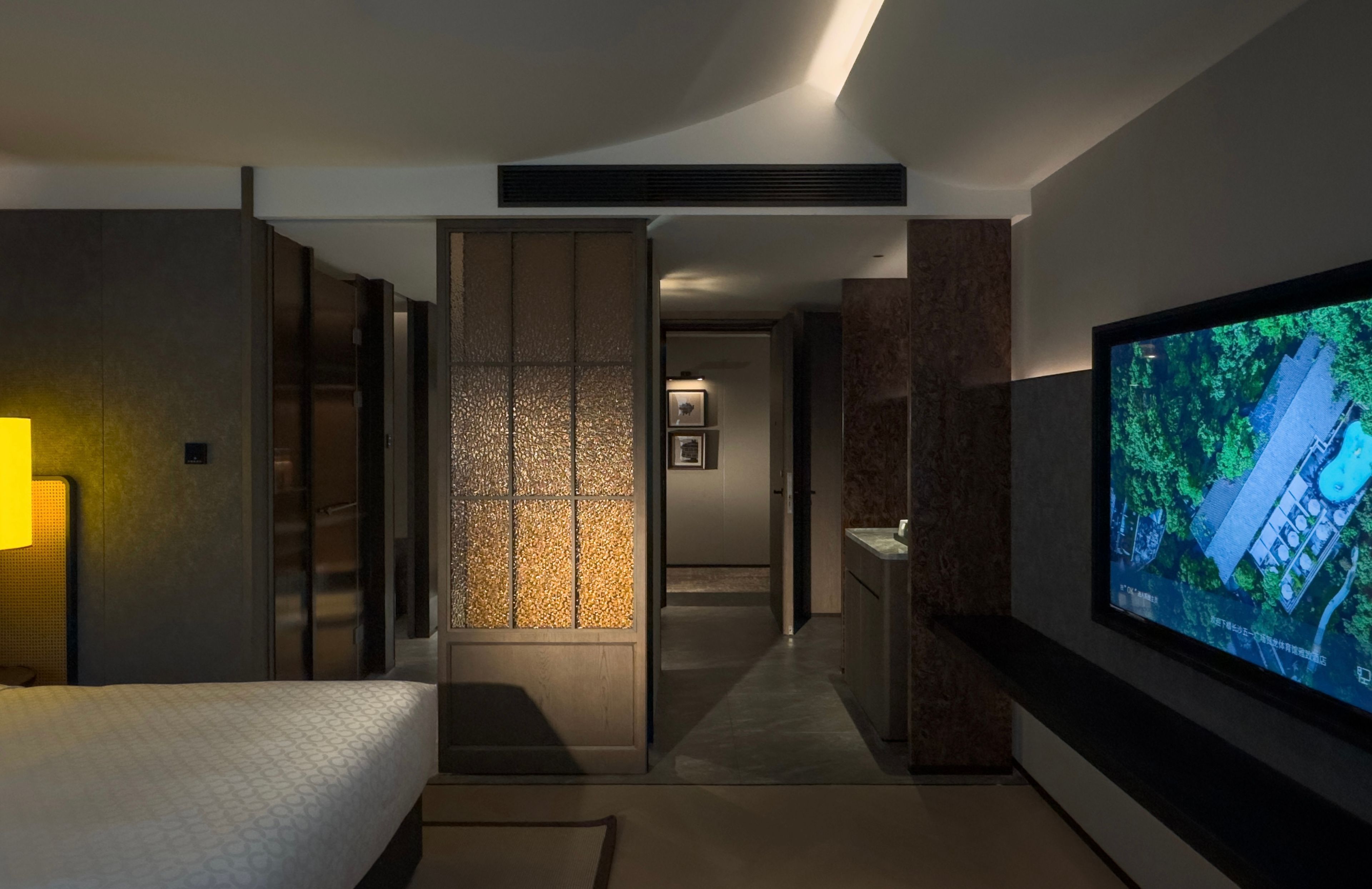 Una habitación de hotel moderna con una cama, un televisor y vista a un edificio a través de una ventana.