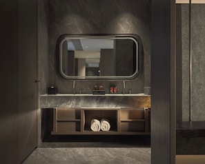 Un baño moderno con tocador de mármol, un espejo grande y repisas empotradas para toallas.