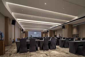 Un salón de conferencias con una larga mesa, sillas y una pantalla de proyección mostrando 'Mehood Elegant Hotel'.