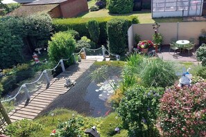 A garden with a wooden deck, a pond, and various plants. - Holiday apartment with 1 bedroom (Norden)