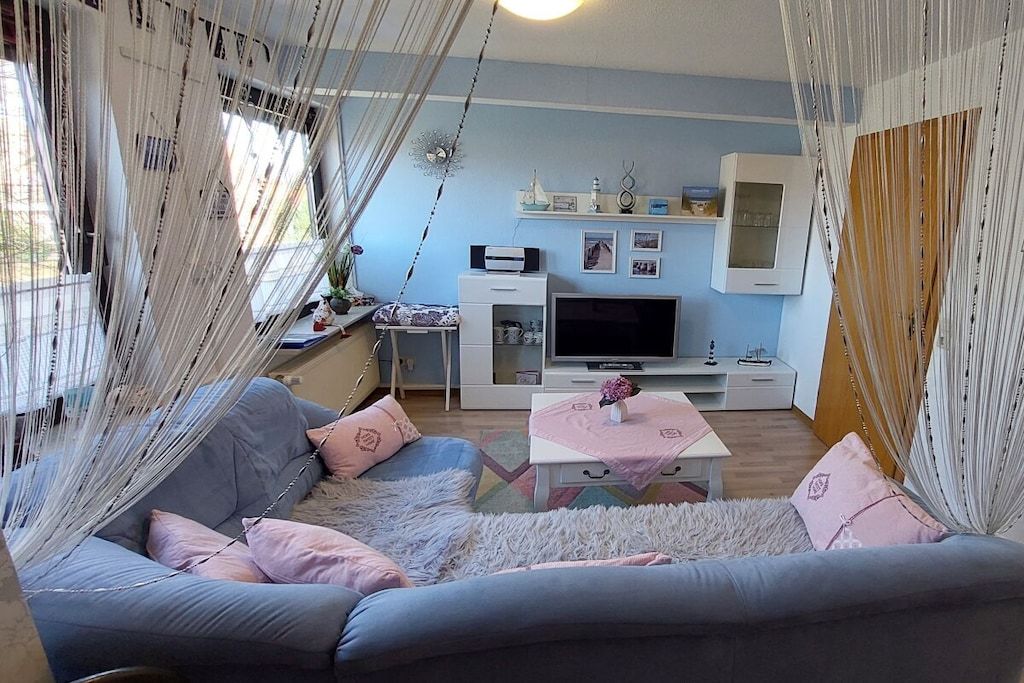 A living room with a sofa, TV, and a small table with a vase.