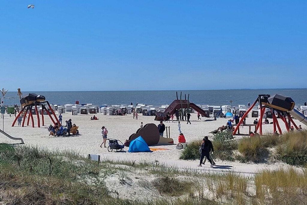 A beach with play structures and beachgoers.