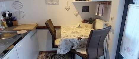Una cocina compacta con comedor, un reloj y un ventanal.