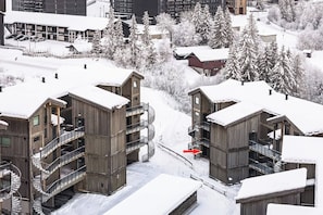 Un edificio de madera de varios pisos con balcones y un paisaje cubierto de nieve.