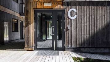 A building entrance with a wooden facade, a glass door, and a large letter 'C' on the wall.