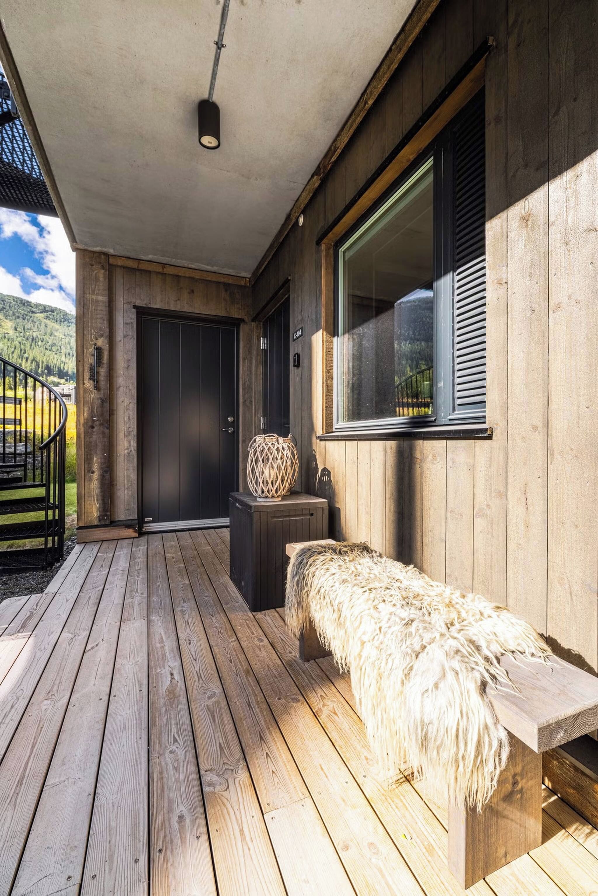 A wooden deck with a bench, a door, and a window.