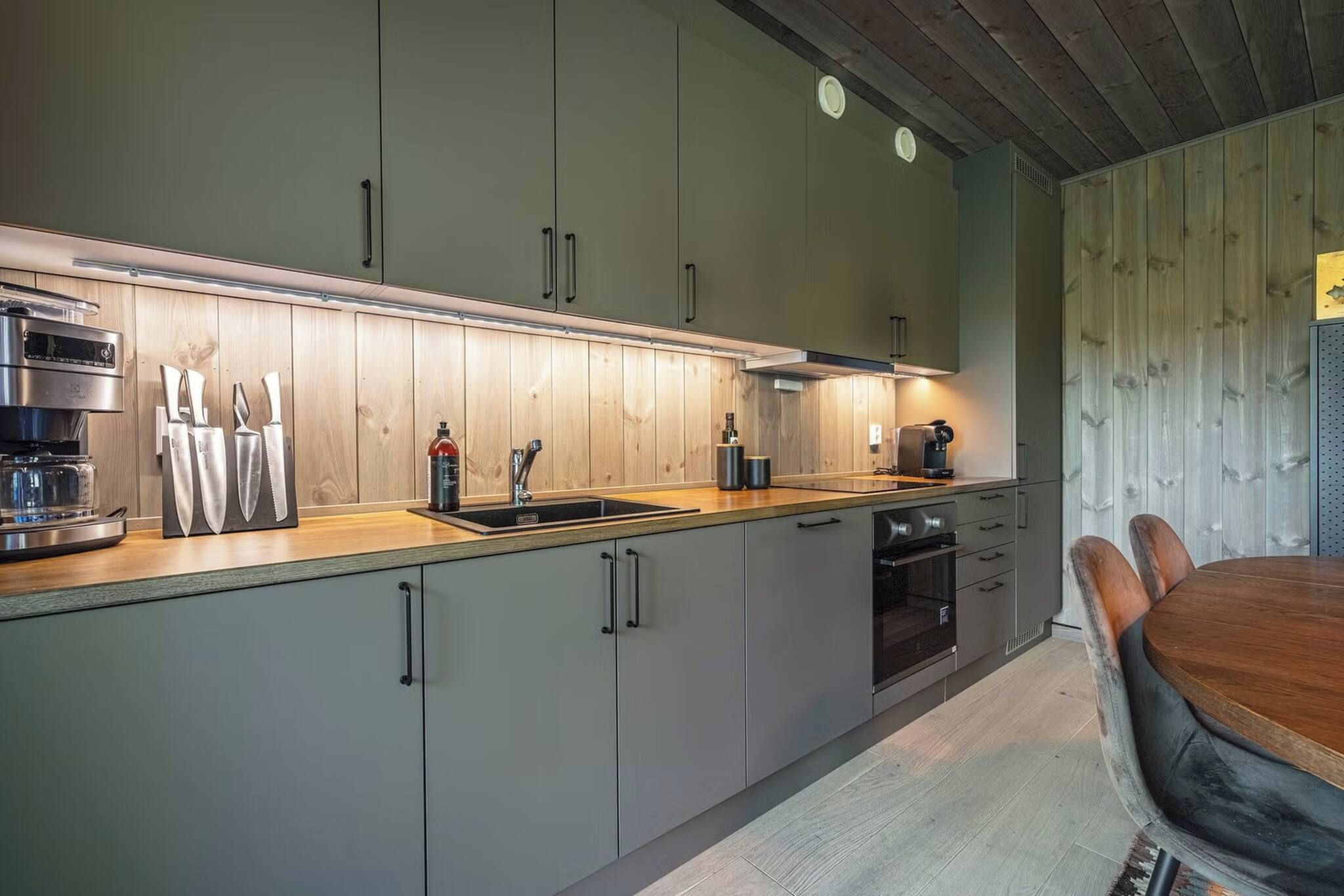 Una cocina moderna con horno empotrado, cafetera y pileta.