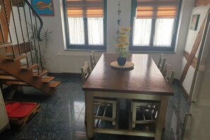 A dining area with a wooden table and chairs, a potted plant, and a staircase. - Casita Priscila || Waren\/Müritz (Waren\/Müritz)