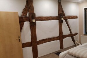 Une chambre avec des poutres apparentes, un lit et une porte.
