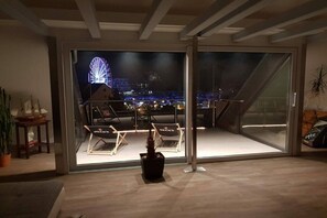 A modern interior with a glass door leading to an outdoor balcony with a city view. - Casita Priscila || Waren\/Müritz (Waren\/Müritz)