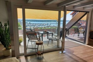 A room with a large sliding glass door leading to an outdoor patio with a view of a marina and boats. - Casita Priscila || Waren\/Müritz (Waren\/Müritz)
