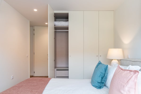 Un dormitorio con cama, lámpara de noche, armario y armario ropero.