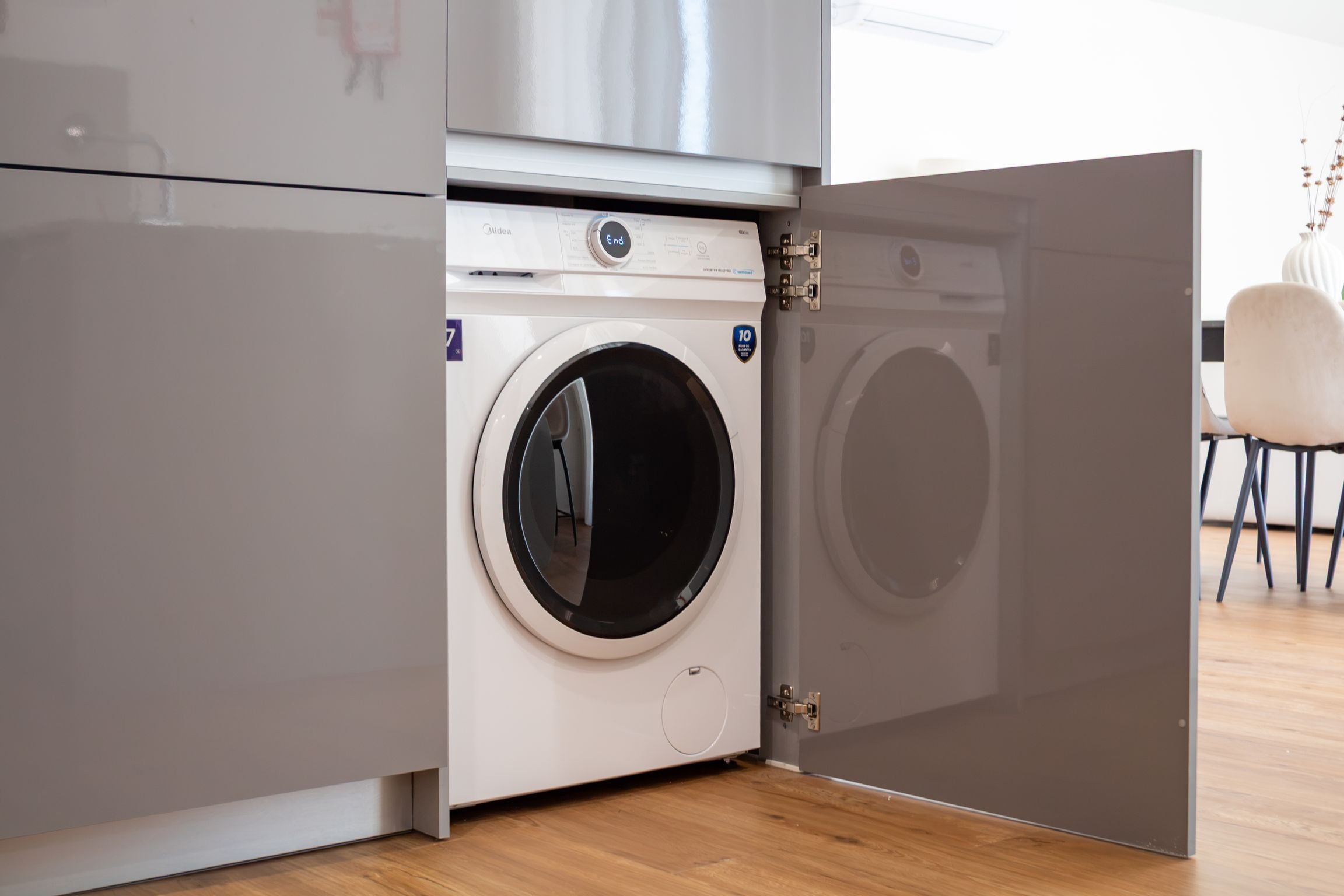 Une petite buanderie moderne, équipée d’un lave-linge à chargement frontal, d’un sèche-linge et d’un meuble de rangement.