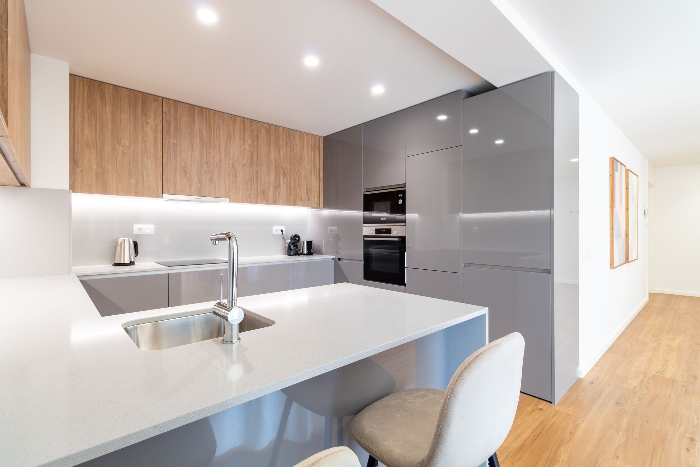 A modern kitchen with a central island, stainless steel appliances, and a wooden accent wall.