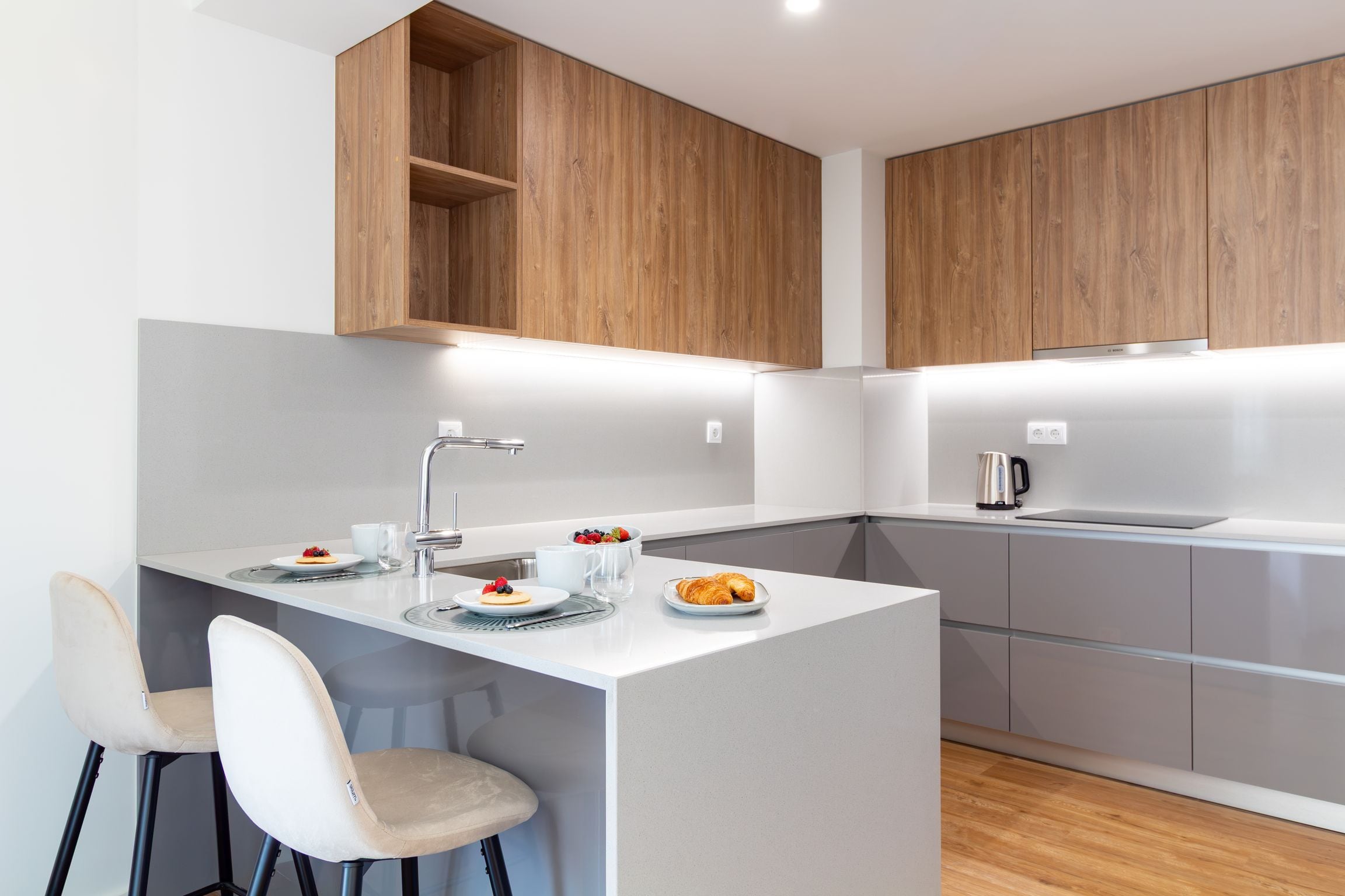 A modern kitchen with a central island, white cabinetry, and a wooden ceiling.