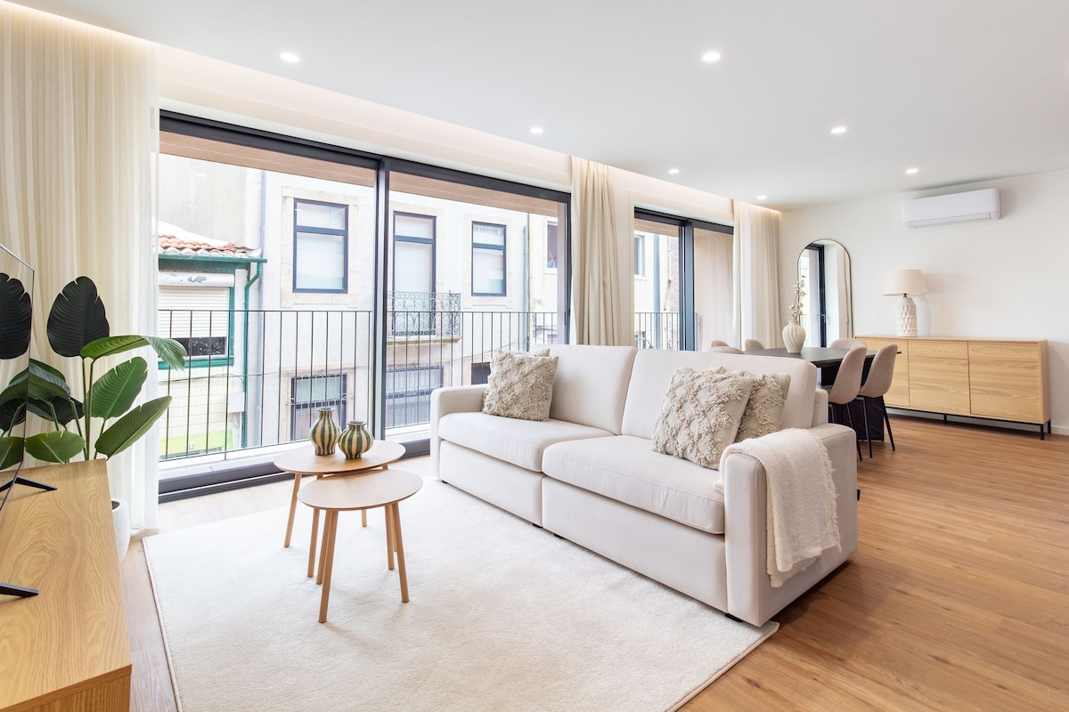 A modern living room with a sofa, a round table, and a view of the outside.